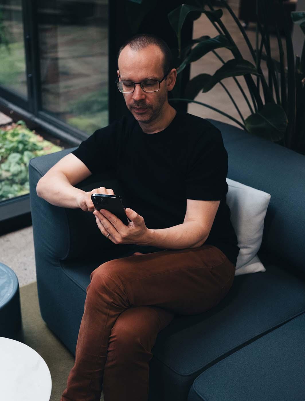 man sitting on sofa with his phone